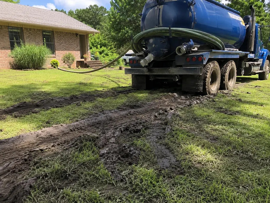 Septic pumping truck with a hose running to a home's septic tank