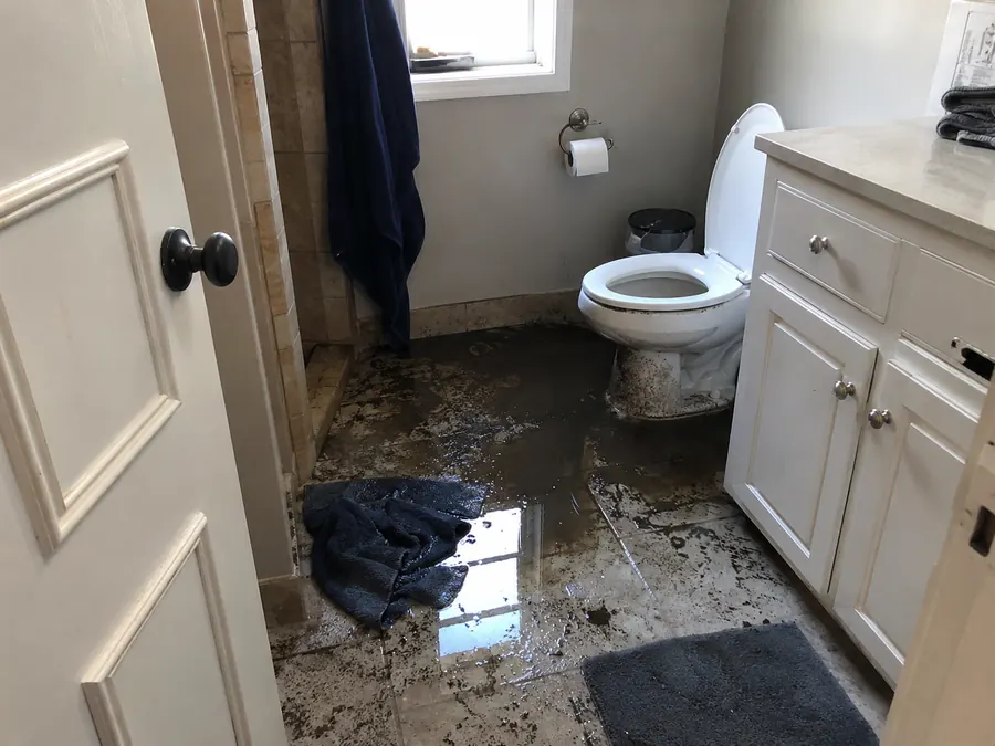 Wastewater on a bathroom floor around a toilet after a septic backup